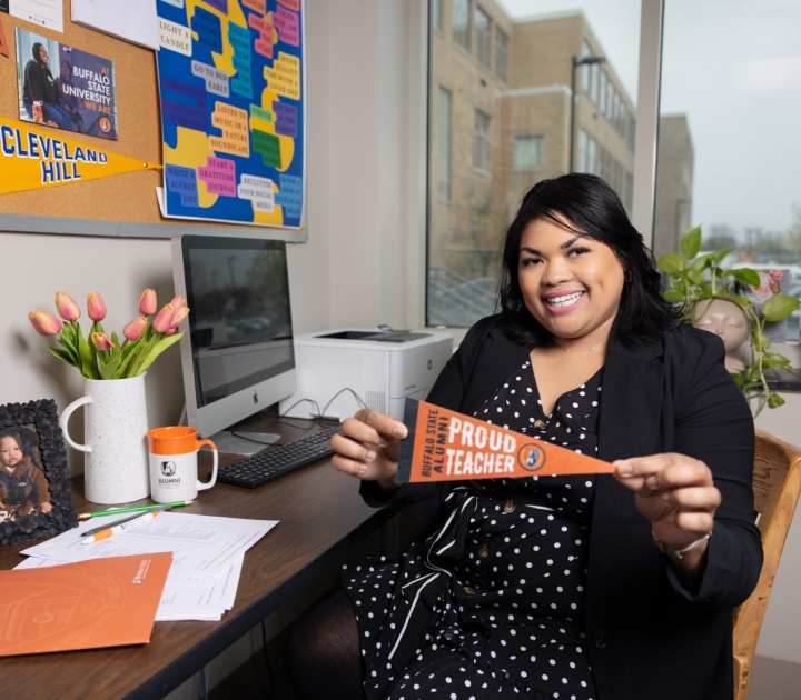 Brianna Ware at desk with Buffalo State alumni banner