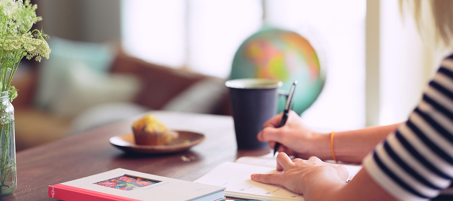 Student writing at a table