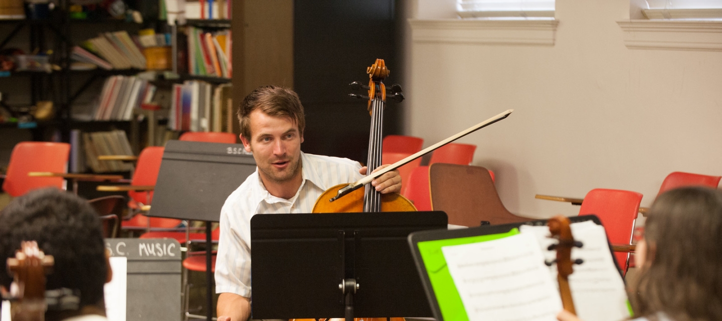 Music teacher with cello instructs students